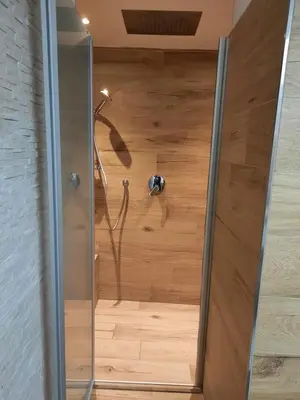 a shower in a room with a wooden floor at Vacanzemoena - Casa al Parco, tipologia 1 in Moena