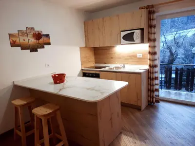 a kitchen with a sink and a counter with stools at Vacanzemoena - Casa al Parco, tipologia 1 in Moena