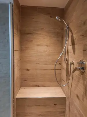 a shower in a bathroom with a wooden wall at Vacanzemoena - Casa al Parco, tipologia 1 in Moena