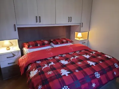 a bedroom with a bed with a red and white blanket at Vacanzemoena - Casa al Parco, tipologia 1 in Moena