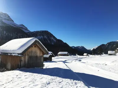 a small wooden building in the snow next to a road at Appartamento San Pellegrino in Passo San Pellegrino