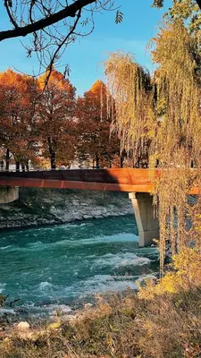 a bridge over a river with some water and trees at Nina • Parchi e Fiume in Bressanone