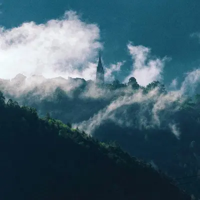 a church on top of a hill in the clouds at Nina • Parchi e Fiume in Bressanone