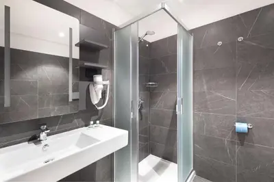a bathroom with a sink and a shower with a mirror at B&B Hotel Bolzano in Bolzano