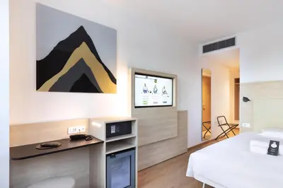 a bedroom with a bed and a desk and a tv at B&B Hotel Bolzano in Bolzano