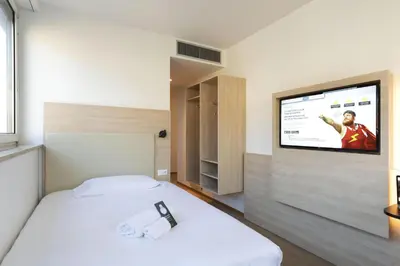 a bedroom with a bed with a flat screen tv on the wall at B&B Hotel Bolzano in Bolzano