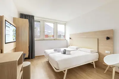a hotel room with two beds and a table at B&B Hotel Bolzano in Bolzano