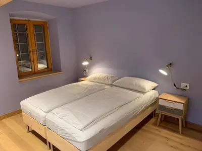 a bedroom with a large white bed and a window at Albergo Stella in Cavalese