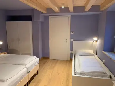 two beds in a room with blue walls and wooden floors at Albergo Stella in Cavalese