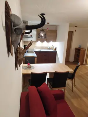 a living room with a red couch and a kitchen at Apartments Ban Guggugg in Colle Isarco