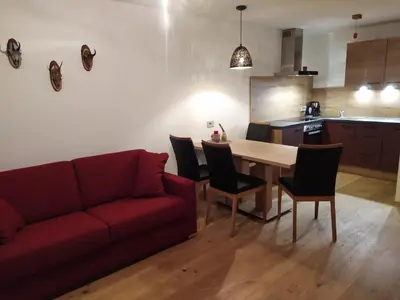 a living room with a red couch and a table at Apartments Ban Guggugg in Colle Isarco