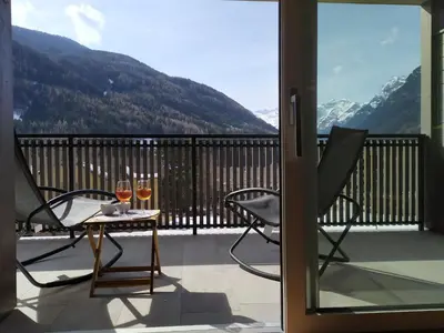 a balcony with two glasses of wine on a table at Apartments Ban Guggugg in Colle Isarco