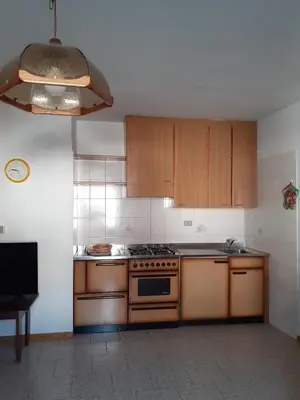 a kitchen with wooden cabinets and a stove top oven at Vacanzemoena - Casa del Moro in Moena