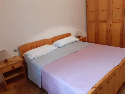 a bedroom with a large white bed and wooden cabinets at Vacanzemoena - Casa del Moro in Moena