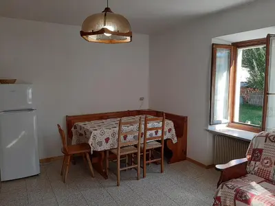 a dining room with a table and a refrigerator at Vacanzemoena - Casa del Moro in Moena