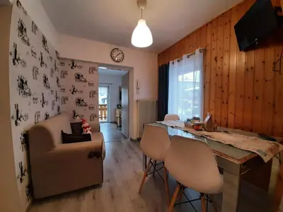 a kitchen and living room with a table and chairs at Appartamento Casa Montagna Lory in Pozza di Fassa