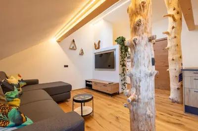 a living room with a couch and a tree at Appartments zum Beck in Eggen