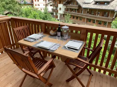 a wooden table with glasses and a bottle of wine on a deck at San Vigilio di Marebbe - Suite di Montagna in San Vigilio Di Marebbe