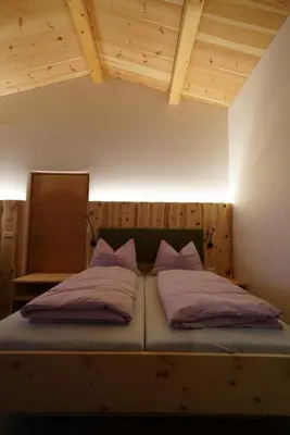 a bed with two pillows on it in a room at NEUE Ferienwohnungen auf dem Gebreitnerhof, Urlaub auf dem Bauernhof in Bressanone