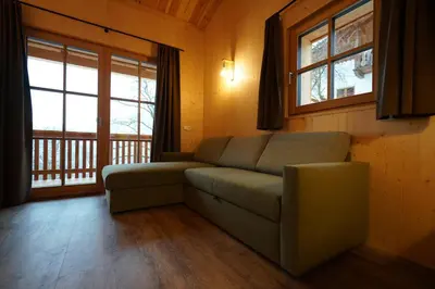 a living room with a couch and two windows at NEUE Ferienwohnungen auf dem Gebreitnerhof, Urlaub auf dem Bauernhof in Bressanone