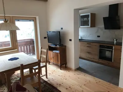a living room with a table and a tv and a kitchen at Cësa Gredine in Ortisei