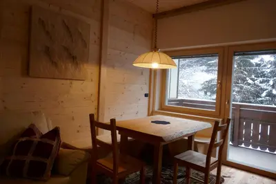 a dining room with a table and chairs and a lamp at Cësa Gredine in Ortisei