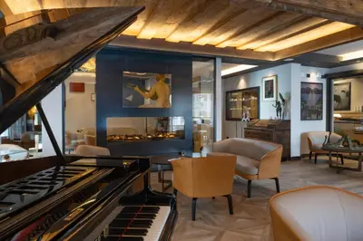 a living room with a fireplace and a piano at Locanda degli Artisti Art Hotel in Canazei
