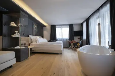 a bathroom with a tub and a bedroom with a bed at Locanda degli Artisti Art Hotel in Canazei