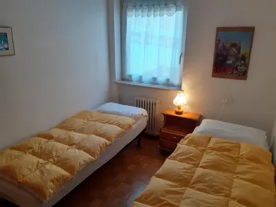 a bedroom with two beds and a window and a lamp at Vacanzemoena - Cielo Azzurro, tipologia 1 in Moena