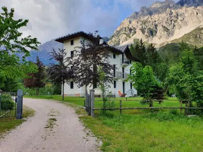 a white house with a fence next to a dirt road at Mansarda 4 posti letto in Villa a Borca di Cadore in Villanova