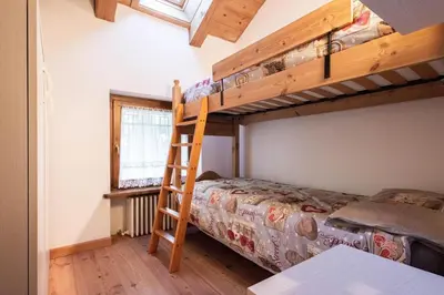 a bedroom with two bunk beds and a ladder at Mansarda 4 posti letto in Villa a Borca di Cadore in Villanova