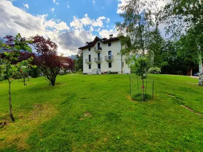 a large white house in the middle of a field at Mansarda 4 posti letto in Villa a Borca di Cadore in Villanova