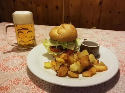 a sandwich and fries on a plate with a glass of beer at Gasthof Thaler in Mezzaselva