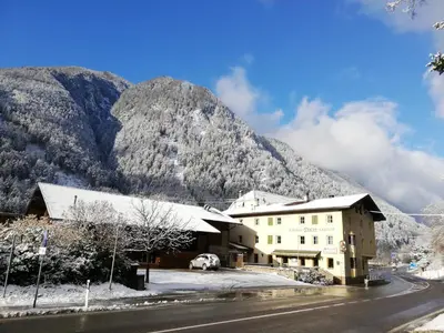 a building on the side of a road with mountains in the background at Gasthof Thaler in Mezzaselva