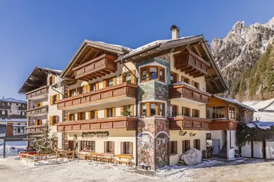 a large building in the mountains with snow at Agritur Broch in Fiera di Primiero