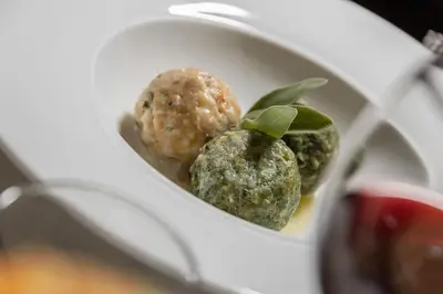 a white bowl filled with balls of food with leaves at Agritur Broch in Fiera di Primiero