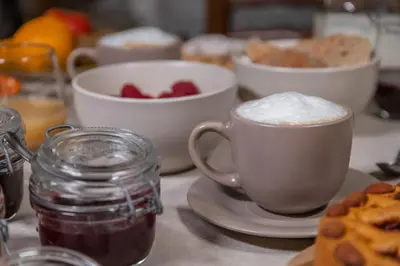 a table with two cups of coffee and a bowl of fruit at Agritur Broch in Fiera di Primiero