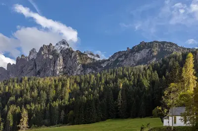 a house in a field with mountains in the background at Agritur Broch in Fiera di Primiero