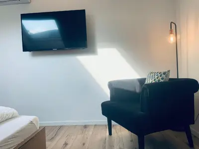 a living room with a chair and a flat screen tv at Apartment Marie in Bolzano