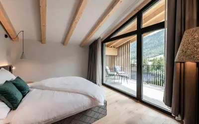 a bedroom with a bed and a large window at Residence Le Fostü in San Vigilio Di Marebbe