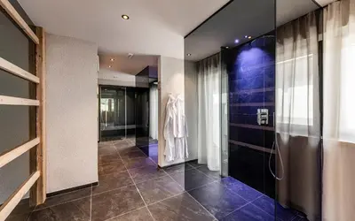 a bathroom with a walk in shower next to a glass door at Residence Le Fostü in San Vigilio Di Marebbe