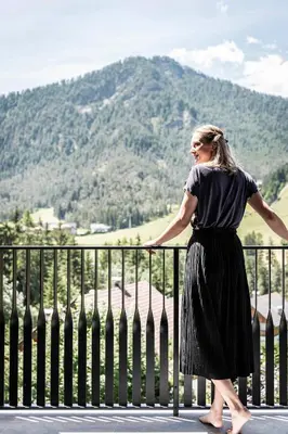 a woman standing on a fence looking at a mountain at Residence Le Fostü in San Vigilio Di Marebbe