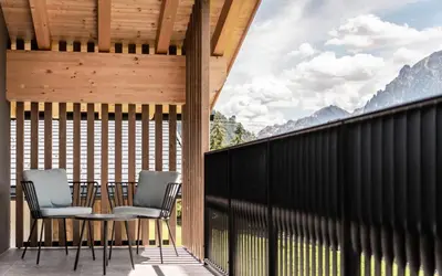 a table and chairs on a balcony with a view of mountains at Residence Le Fostü in San Vigilio Di Marebbe