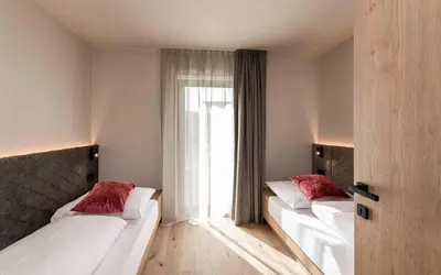 two beds in a room with a window at Residence Le Fostü in San Vigilio Di Marebbe
