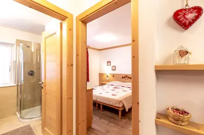 a room with a bed and a glass door leading to a bedroom at Majon Viva in Campitello di Fassa