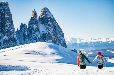 two people walking on a snow covered mountain at Binterhof in Castelrotto