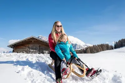 a woman and a child sitting in the snow at Binterhof in Castelrotto