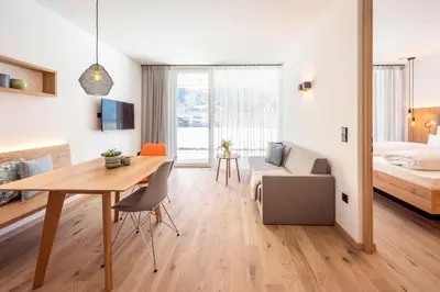 a living room with a dining room table and a bedroom at Das Heacher in Merano