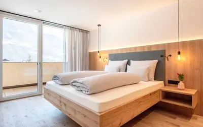 a bedroom with a large bed with a large window at Das Heacher in Merano