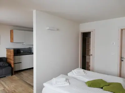 a white room with a bed and a kitchen at Casa Lassù in Carano